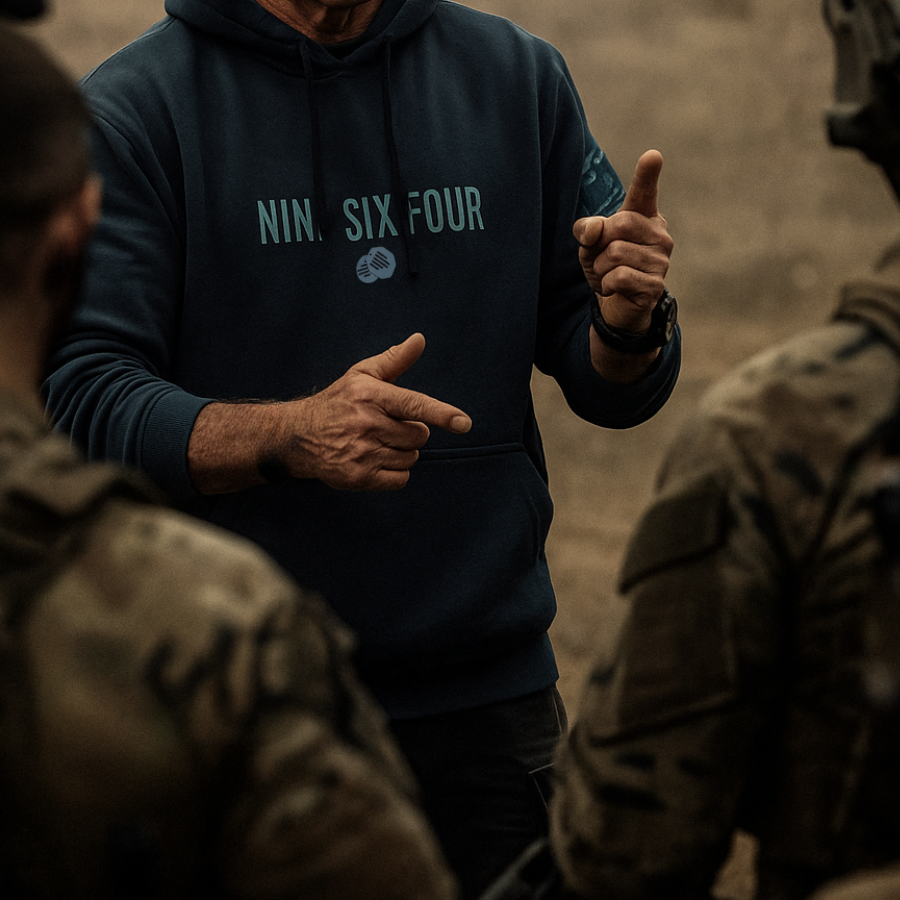 Man wearing official SAS merchandise hoodie by NINESIXFOUR while briefing soldiers outdoors