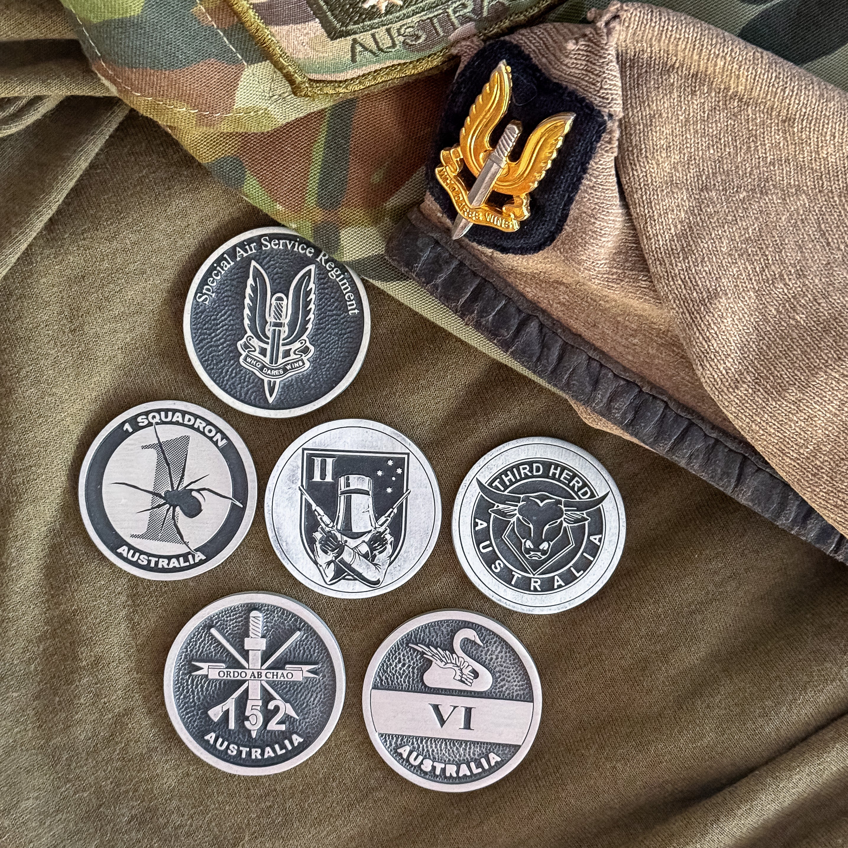 ninesixfour SASR challenge coin set featuring six detailed coins with military insignia on camouflage and fabric background