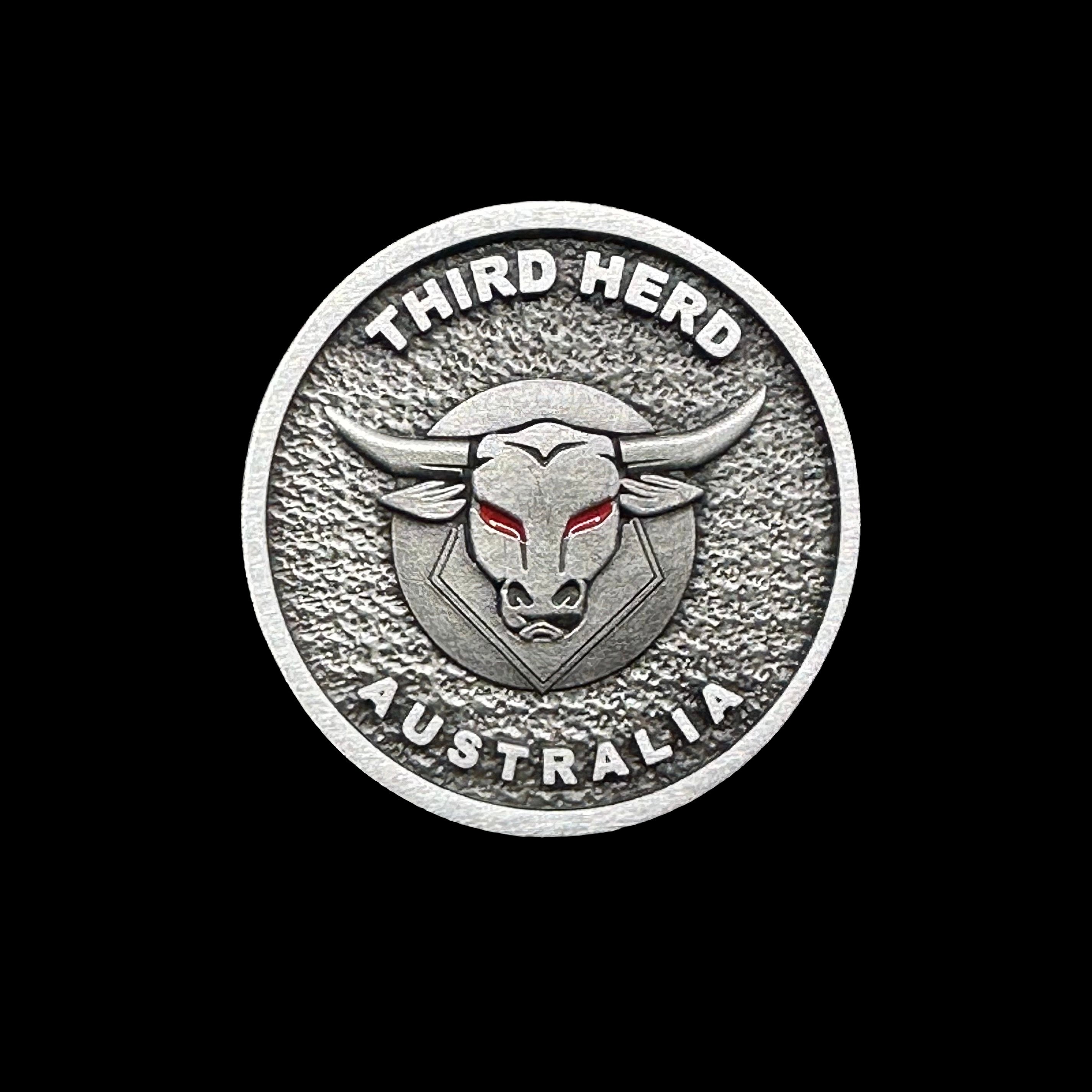 Circular metal Third Herd Australia emblem with bull head and red eyes on textured background