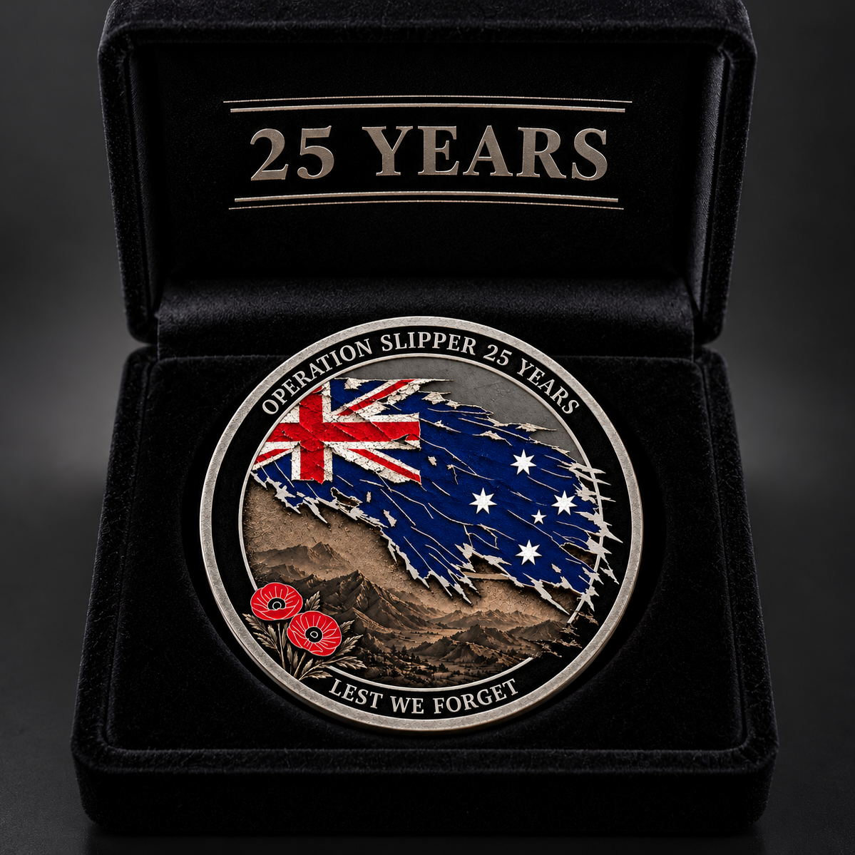 A commemorative oval coin for Operation Slipper 25 Years, displayed inside an open black velvet presentation box with '25 YEARS' engraved on the lid. The coin features a distressed Australian flag design with the Union Jack and stars, a brown mountain landscape, and red poppy emblems, with the text 'OPERATION SLIPPER 25 YEARS' and 'LEST WE FORGET'.
