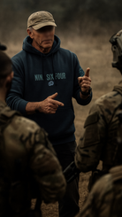 Man wearing official SAS merchandise hoodie by NINESIXFOUR while briefing soldiers outdoors