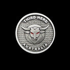 Circular metal Third Herd Australia emblem with bull head and red eyes on textured background